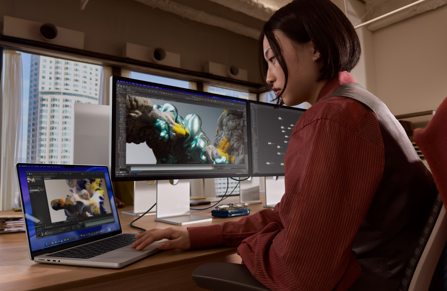Une personne dans un bureau travaille sur un MacBook connecté à un Studio Display XDR via un port Thunderbolt 5